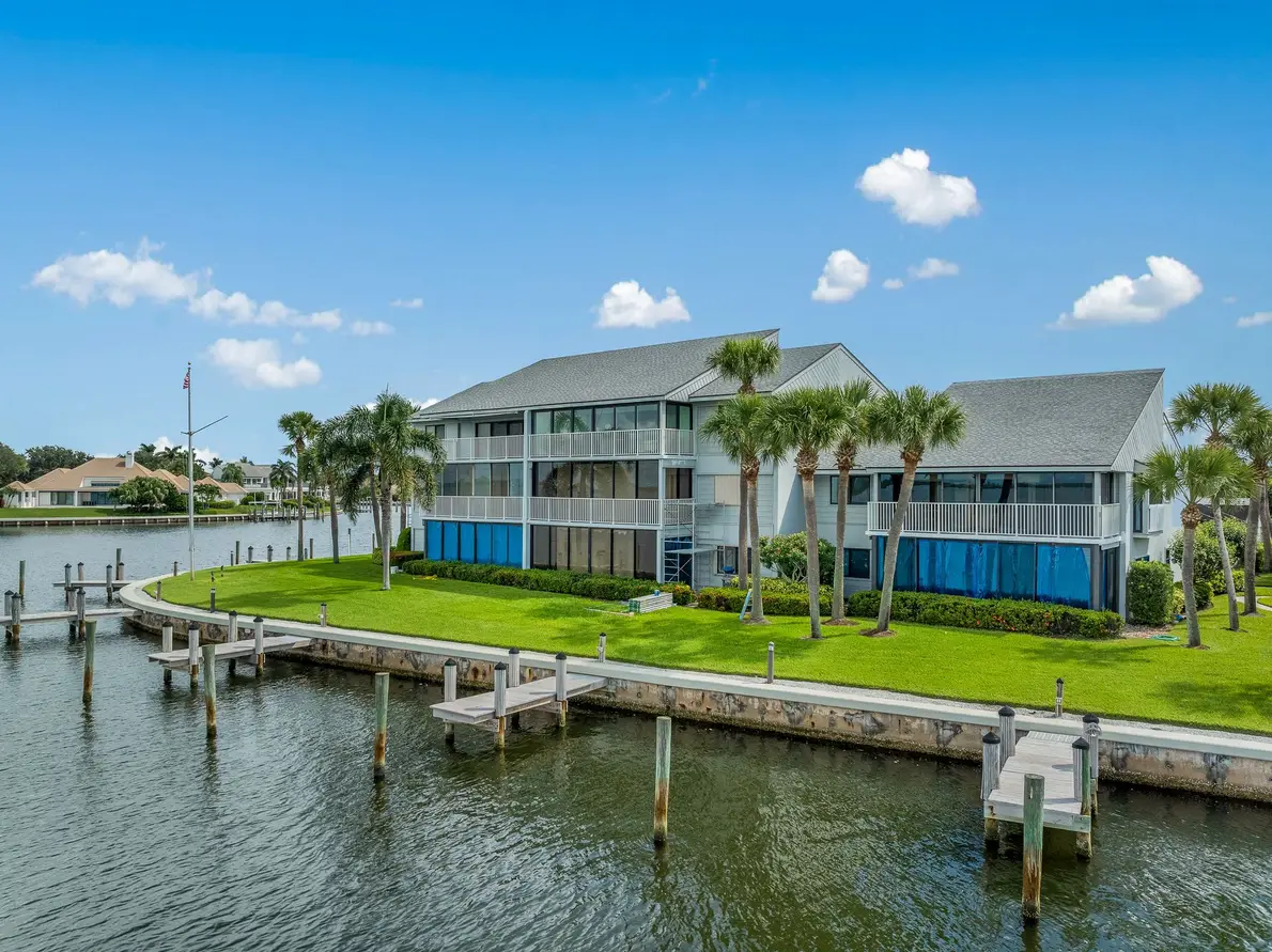 1776 Mooringline Drive, PH-C: the waterfront elevation with seawall, dock and mature palms