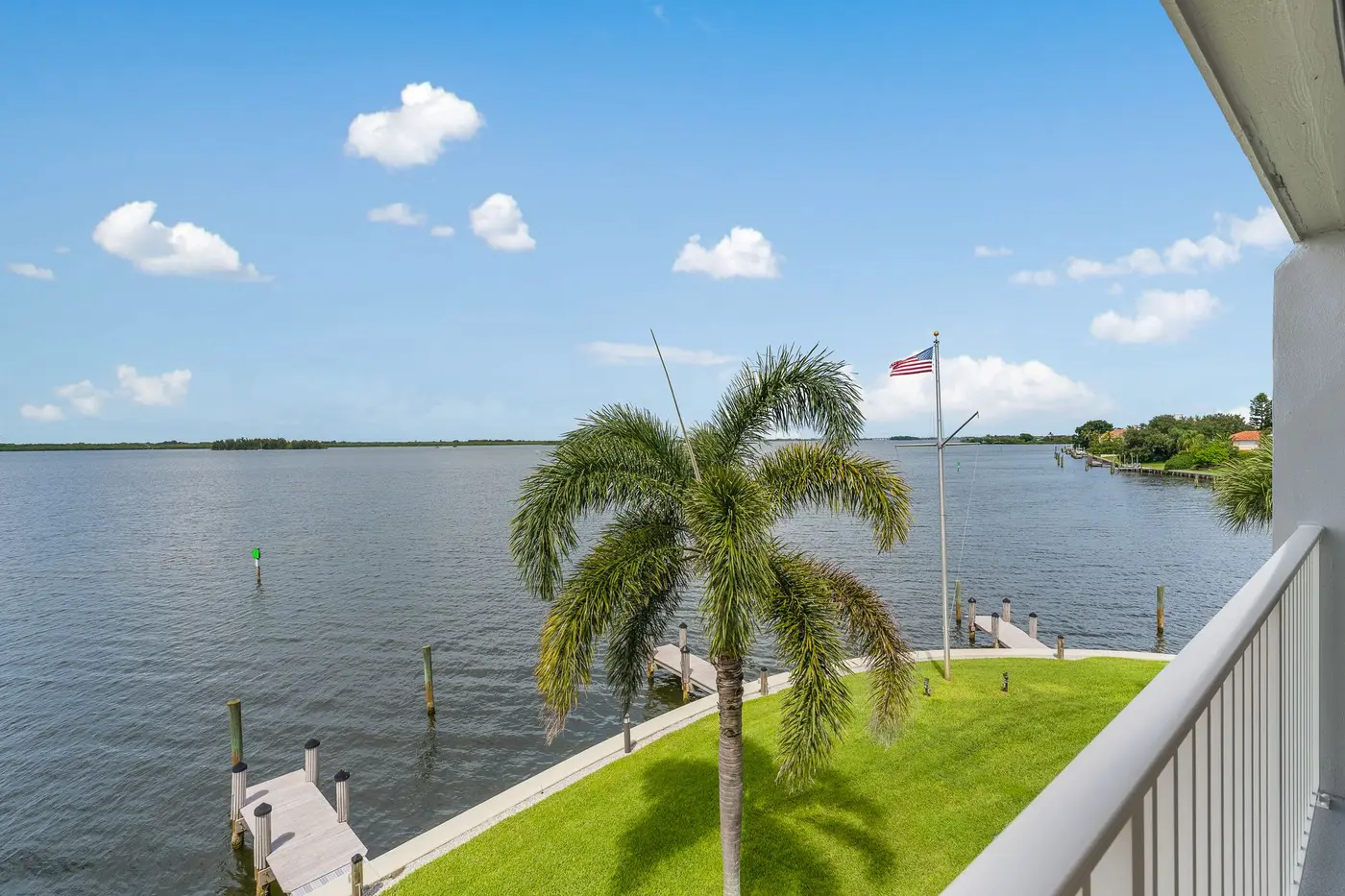 1776 Mooringline Drive, PH-C: the lawn, palms and dock from the terrace, looking west across the lagoon