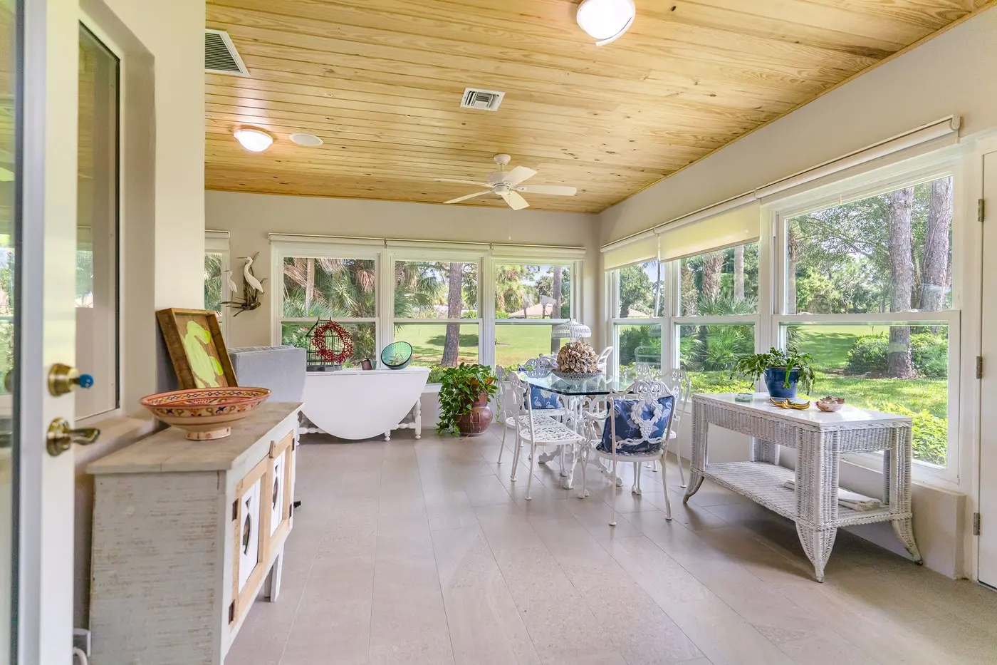 5795 Magnolia Lane: the Florida room, a long wall of windows under a wood ceiling facing the golf course